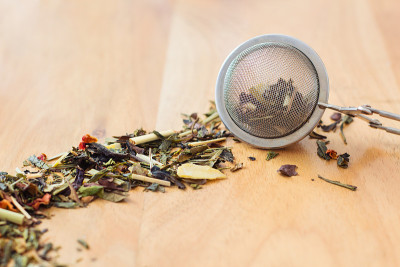 木质背景上的散叶茶和滤茶器