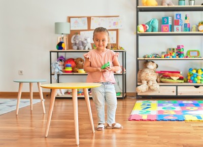 美丽的金发小女孩在幼儿园玩塑料青蛙玩具