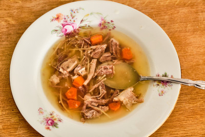 美味的自制牛肉肉汤，胡萝卜面条，白色的盘子和勺子放在木桌上