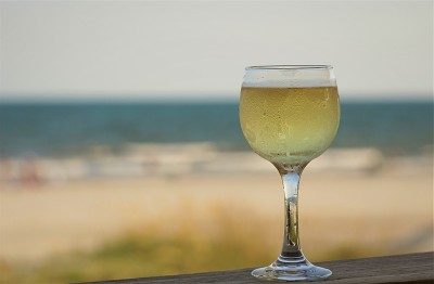 一杯白葡萄酒在海滩和海洋的背景