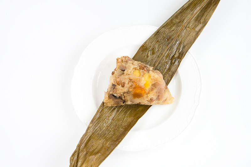 中国粽子(粽子)塞满花生，蘑菇，甜芋泥，卤蒸猪肉，银杏叶和咸蛋黄在竹叶和白色盘子