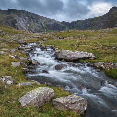 秋天，在斯诺登尼亚的Llyn Ogwen和Llyn Idwal附近，一条河流顺着山脉流下的穆迪景观图