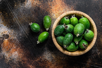 绿色的feijoa水果在一个木制的盘子在黑暗的背景。热带水果费约果。前视图。空间的文本