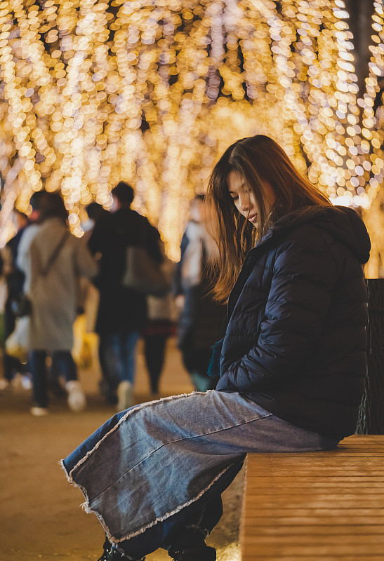 美丽的女人肖像坐在冬天的衣服在晚上，在日本仙台市中真寺圣诞灯光节日