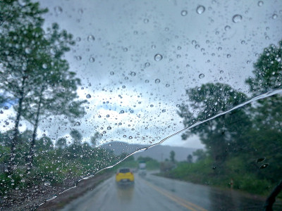 雨点落在挡风玻璃上，在下雨和湿滑的道路上，会造成视觉障碍和危险驾驶。从汽车座位上看。