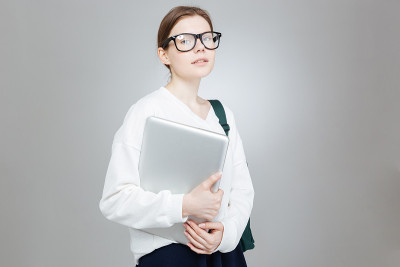 漂亮的女学生戴着眼镜和笔记本电脑的肖像