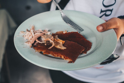 手捧一盘广受欢迎的美味烤猪或“lechon baby”皮和肉酥脆