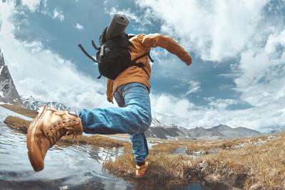 一个徒步旅行者在山区跳过水