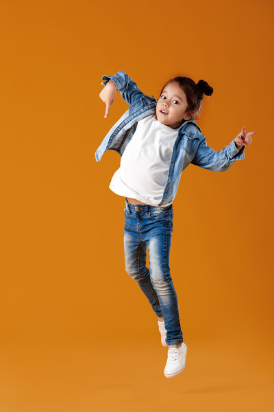 快乐的小女孩穿着牛仔裤衣服跳