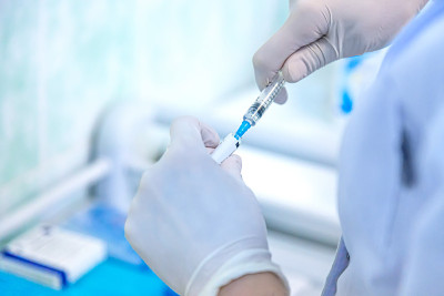 概念对抗新冠病毒。实验室里拿着装有液体疫苗注射器的科学家或医生