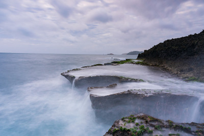 在雨季，海岸上有波浪和青苔的沉积岩海滩