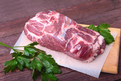 生猪颈剁肉和欧芹叶在石头背景上。准备做饭。