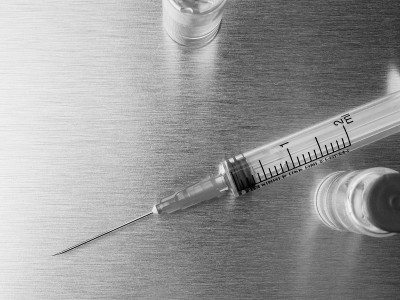 在抛光的金属背景上放置注射器和安瓿。