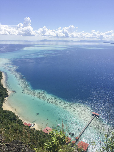 从最令人惊叹的山峰Bohey Dulang上鸟瞰蔚蓝的大海，海水、珊瑚、山和天空的图案。