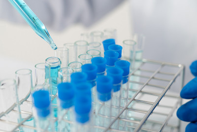 生物化学实验室研究，科学家或医务人员在实验室工作的玻璃设备上，穿着实验室大褂，拿着带有彩色液体的使用