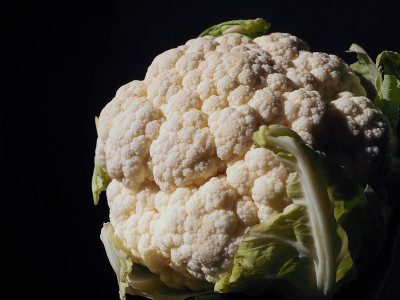 花椰菜特写在一个黑色的背景。边点燃。新鲜的卷心菜头。绿色蔬菜。十字花科芸薹属的甘蓝。健康饮食和素食主