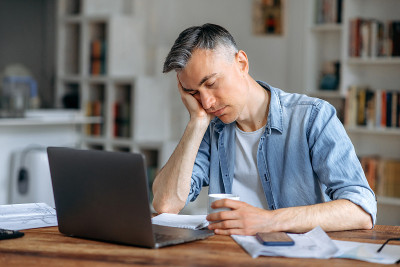 一位睡意朦胧、魅力四射、头发花白的高级经理、自由职业者或办公室职员，穿着休闲装，在工作时趴在笔记本电