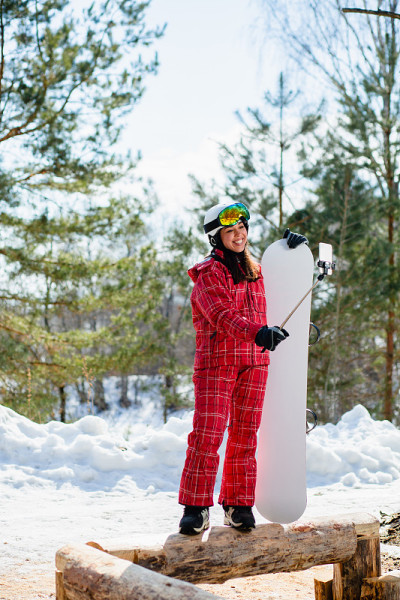 一名女子拿着滑雪板，把智能手机放在棍子上自拍