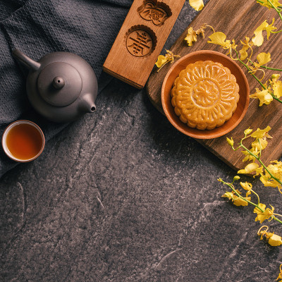 中秋节传统食品概念-美丽的月饼在黑石板桌上用茶，糕点模具，花。