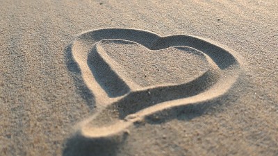 在沙滩上画心形，日落时被海浪抹去