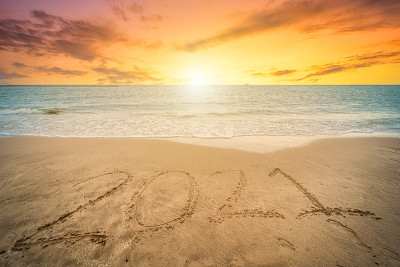 2021年新年快乐文本美丽的海滩与波浪清晨日出在地平线上的背景。在圣诞节和新年期间。