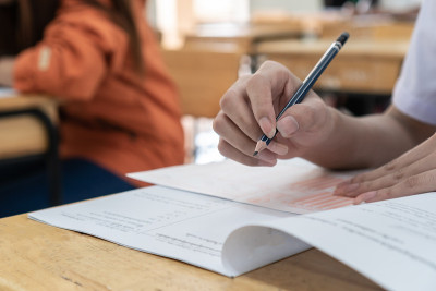 学校/大学的学生手拿考试，用铅笔写在光学形式的答卷上，在课桌上做期末考试。教育评估的概念