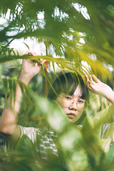 年轻的成年亚洲妇女在家花园与树叶。