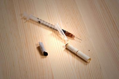 木制的工作台面上放着注射器和几个烟头