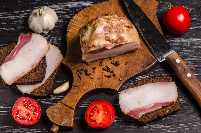 黑木桌上放着多汁的熏肉、三明治、香料和生蔬菜。