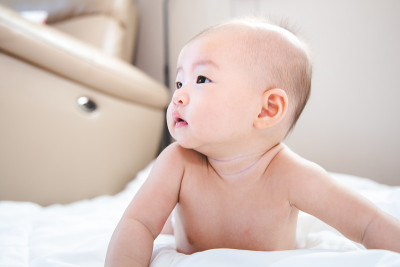 亚洲宝宝在房间里很开心。亚洲女婴躺在床上。