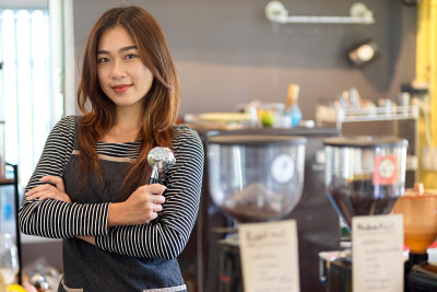 有魅力的美女亚洲女咖啡师站在柜台前，拿着过滤嘴