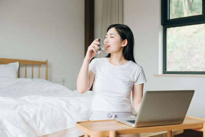 年轻的亚洲女孩在床上使用笔记本电脑