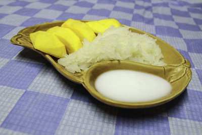 泰国甜品，芒果糯米饭在陶瓷盘子上涂上棕色。