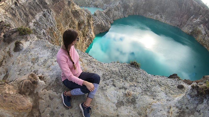 克里穆图-一个正在欣赏蓝绿色火山湖的女孩