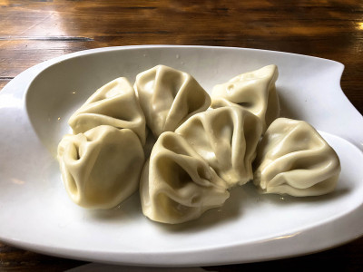 美味的白色传统大面粉格鲁吉亚圆khinkali蒸躺在一个盘子在咖啡馆的木桌上