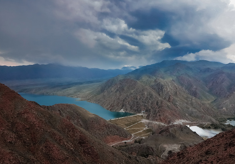 巴尔托盖水库和大坝在哈萨克斯坦的草原山脉之间的巧克力山多云的天气