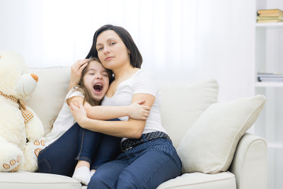幸福微笑的母女在沙发上拥抱。