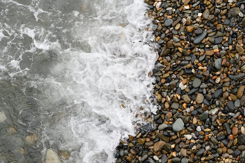 夏日里海浪拍打着卵石滩。前视图。背景为海洋，海滩和度假的主题。