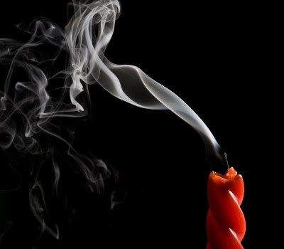 刚熄灭的蜡烛，火焰冒出的烟仍在黑色背景下冒出来。