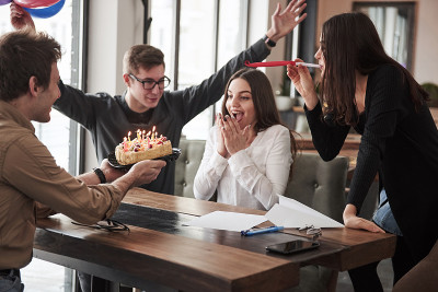 给漂亮的黑发姑娘一个惊喜。一个员工今天过生日。友好的同事决定给她一个惊喜