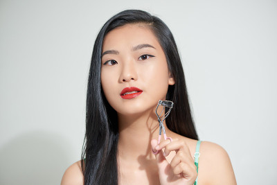少女使她的睫毛更宽与卷发器