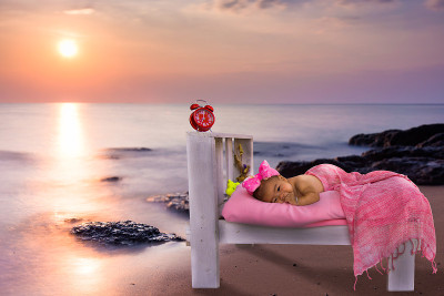快乐的孩子躺在夕阳下的海滩上。