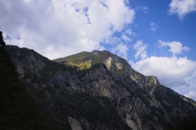 一束光照亮了布满岩石的山顶，绿色的草地(意大利马尔凯的西比里尼国家公园)