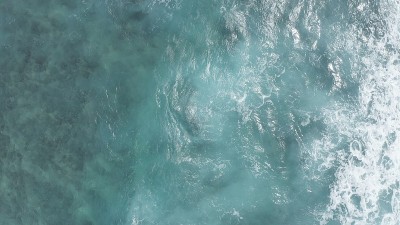 在黄金时刻飞过海洋。巨大的波浪在海洋中激起泡沫和水花。夏威夷瓦胡岛上的太平洋海水的蓝绿色。