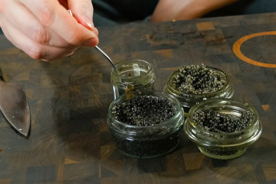 用勺子在玻璃罐中搅拌黑鱼子酱。