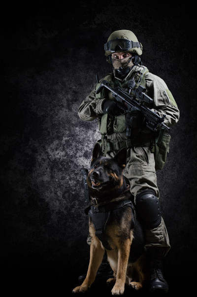 一名全副武装的特种部队士兵手持机关枪和他的牧羊人站在一起