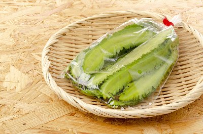 在胶合板的背景上，竹筛上的新鲜翼豆塑料袋