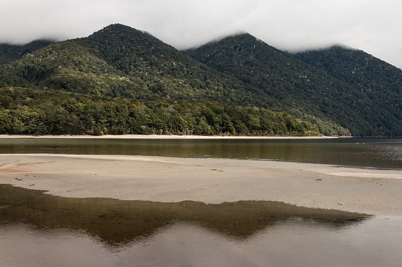 森林覆盖的山坡反射在马纳波里湖