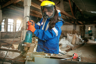 戴头盔的妇女使用男性工作工具