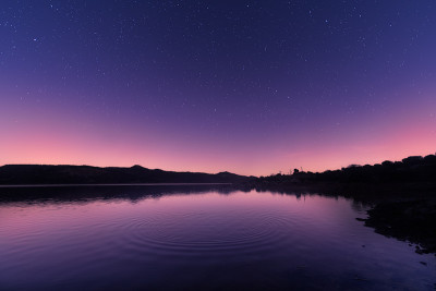在满是星星的紫色天空下，湖面上泛起阵阵涟漪
